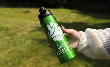 A green, stainless steal water bottle with the QC logo.